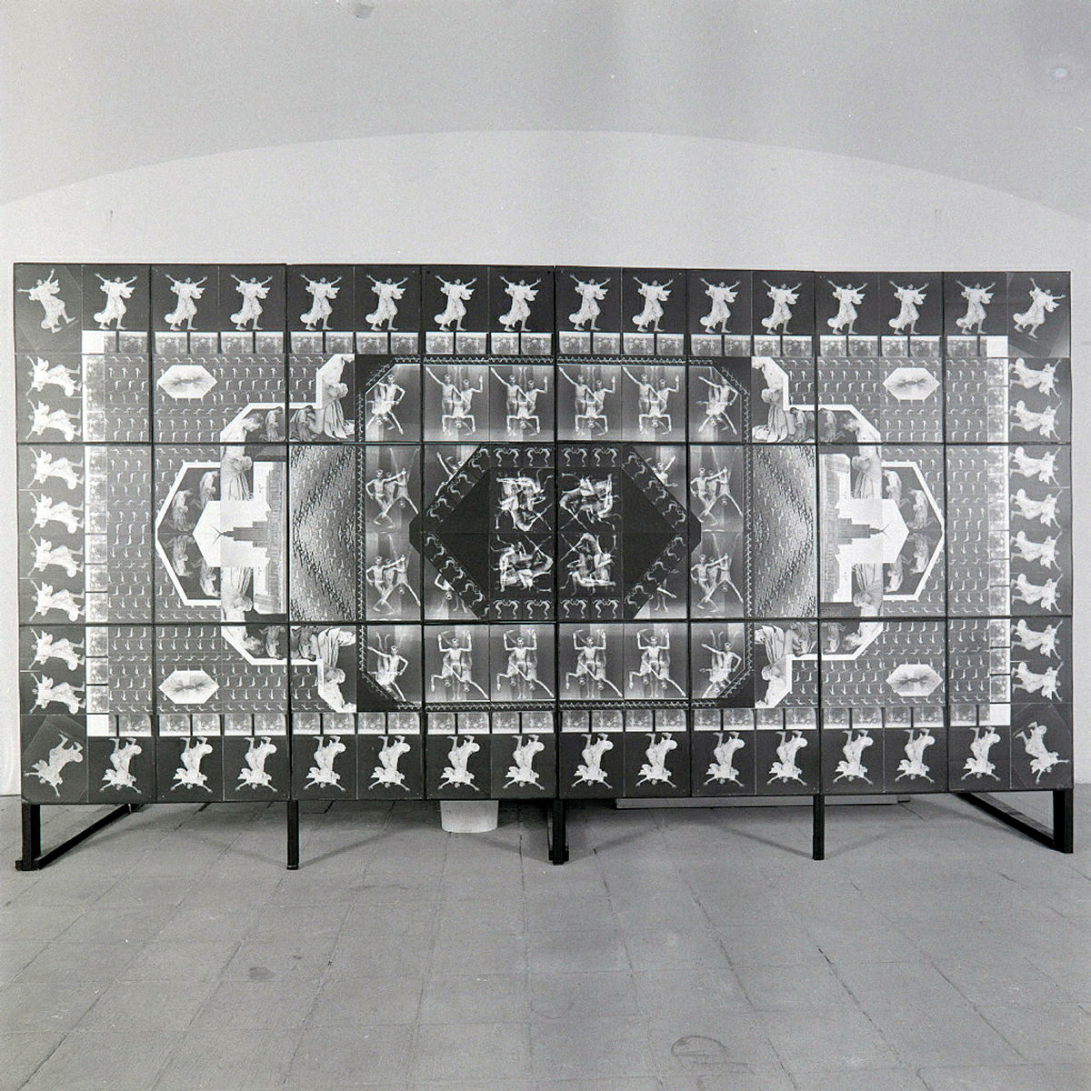 Praca pt. "Idiomy Socwiecza.Fotodywan z motywem Ludzkim z 1989r; Instalacja zlożona z  24 fotografii, 82 x 61 cm każda; 246 x 480 cm całość; fotografia czarno-biała na podłożu barytowym; model: Zbigniew Libera