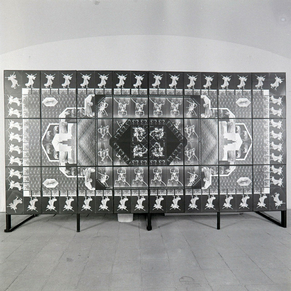 Praca pt. "Idiomy Socwiecza.Fotodywan z motywem Ludzkim z 1989r; Instalacja zlożona z  24 fotografii, 82 x 61 cm każda; 246 x 480 cm całość; fotografia czarno-biała na podłożu barytowym; model: Zbigniew Libera